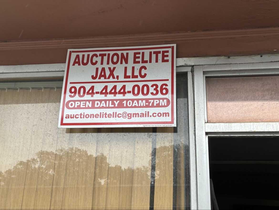 Auction Elite Jax storefront sign with phone number and daily hours